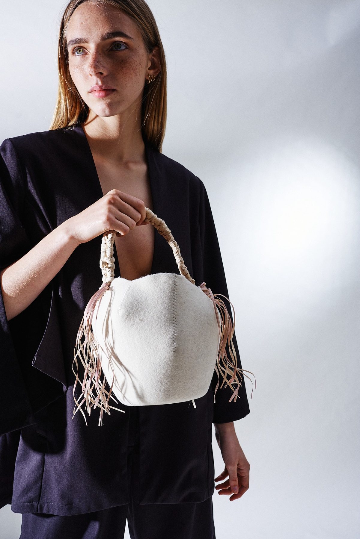Model holding a white felt handbag